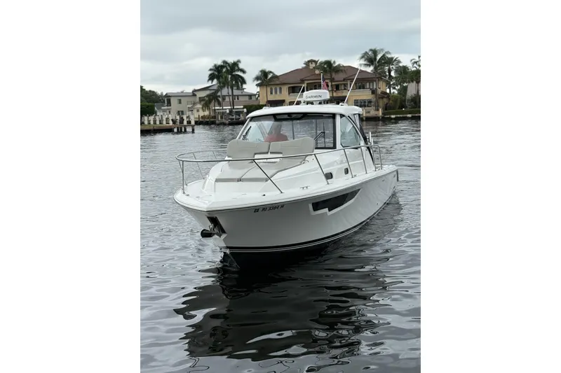 Slide: The Image of 2025 Pursuit OS 325 Offshore boat on calm water near waterfront homes. - 2