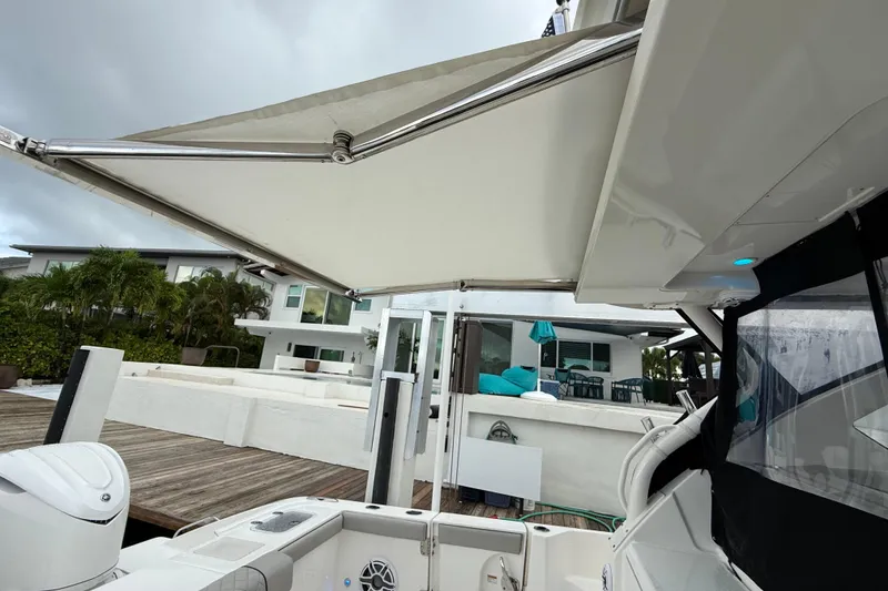 Slide: The Image of 2025 Pursuit OS 325 Offshore boat with extended canopy, docked near modern waterfront home. - 25