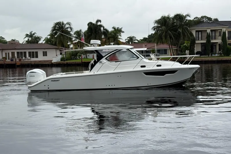 Slide: The Image of 2025 Pursuit OS 325 Offshore boat on calm water near waterfront homes. - 3