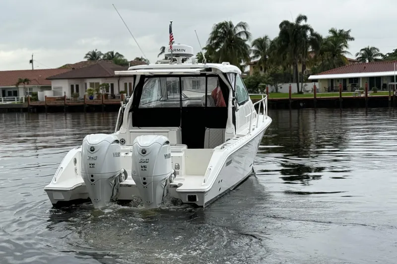 Slide: The Image of 2025 Pursuit OS 325 Offshore boat with twin Yamaha engines on a calm waterway. - 5