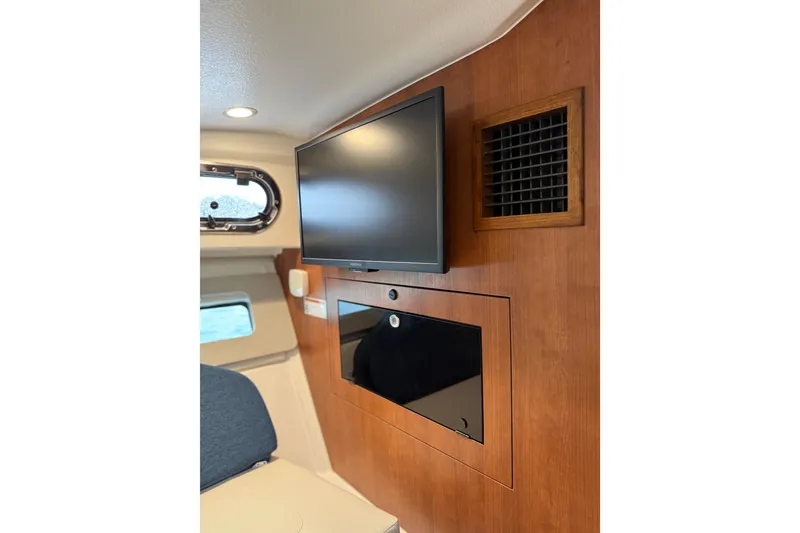 Slide: The Image of 2025 Pursuit OS 325 Offshore cabin interior with TV and wooden paneling. - 60
