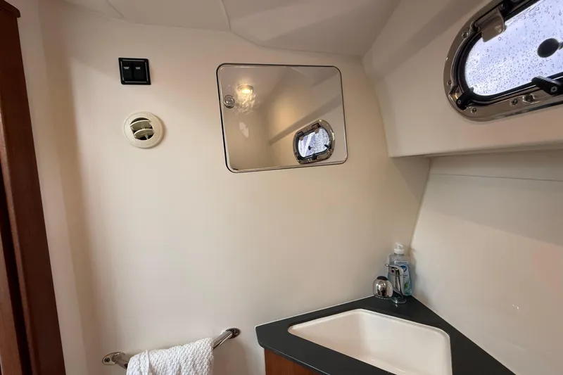Slide: The Image of 2025 Pursuit OS 325 Offshore bathroom with sink, mirror, and porthole window. - 70