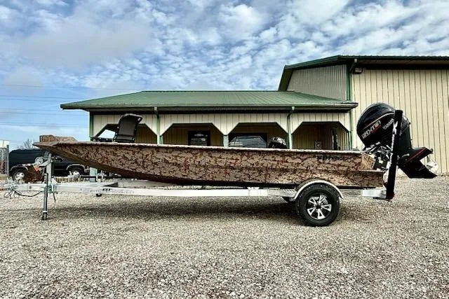 The Image of 2026 Xpress X18DB boat with camouflage design on a trailer, parked outside a building. - 1