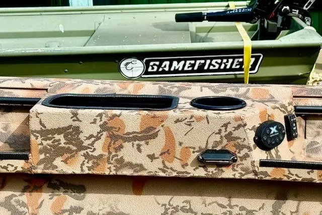 Slide: The Image of Camouflage-patterned Xpress X18DB boat interior, 2026 model, with Gamefisher branding in the background. - 5