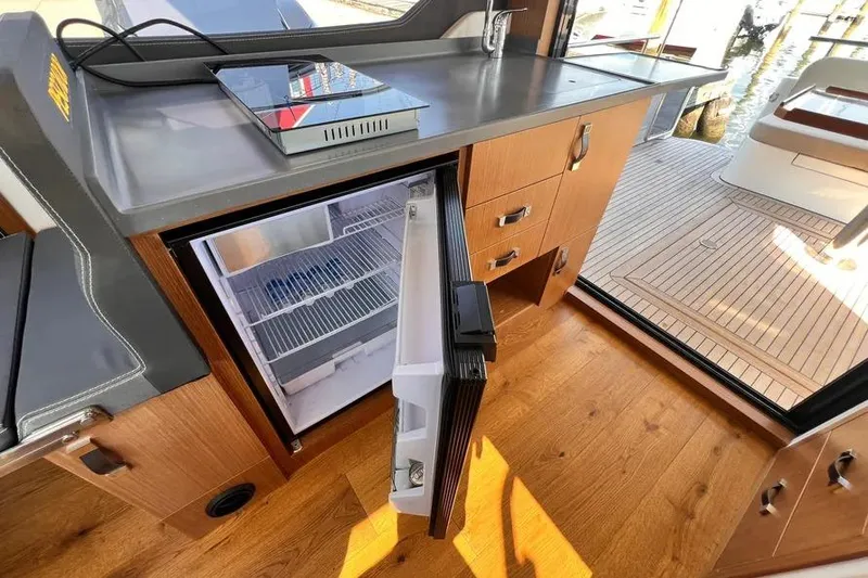 Slide: The Image of Modern kitchen area on 2023 Pescador 35 boat with open fridge and wooden flooring. - 14