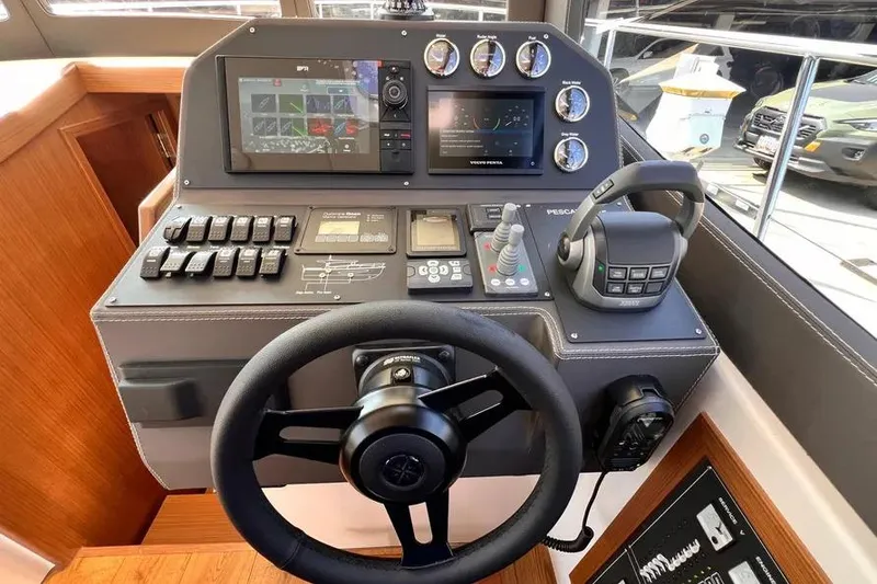 Slide: The Image of 2023 Pescador 35 boat dashboard with steering wheel, controls, and navigation screens. - 31