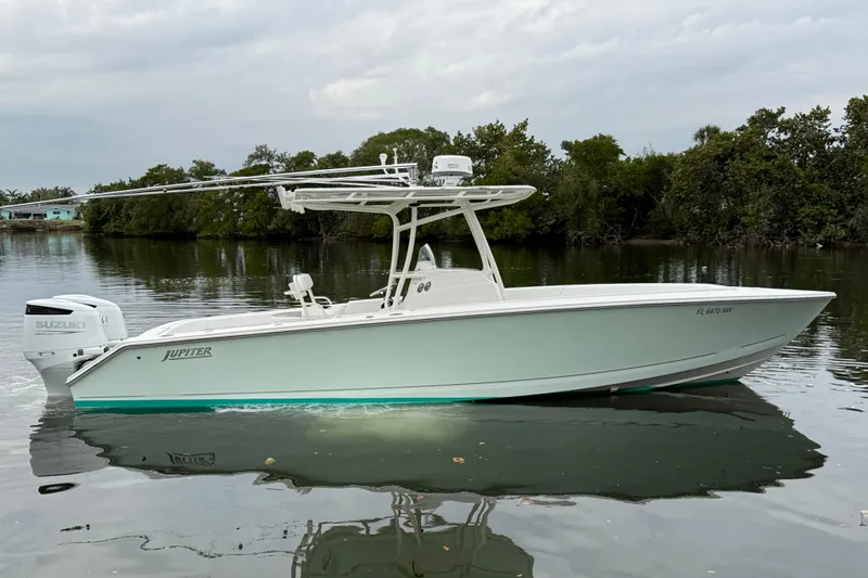 The Image of 2009 Jupiter 29 boat with Suzuki engine on calm water, surrounded by greenery. - 0