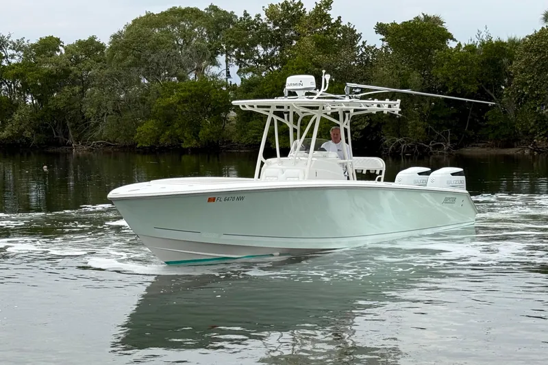 Slide: The Image of 2009 Jupiter 29 boat cruising on calm water near lush greenery. - 2