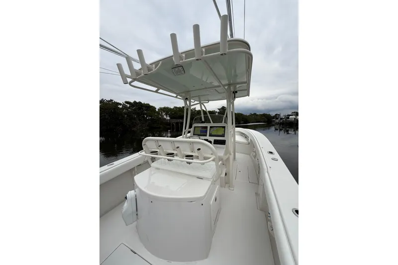 Slide: The Image of 2009 Jupiter 29 boat interior with helm, seating, and rod holders on a calm waterway. - 35