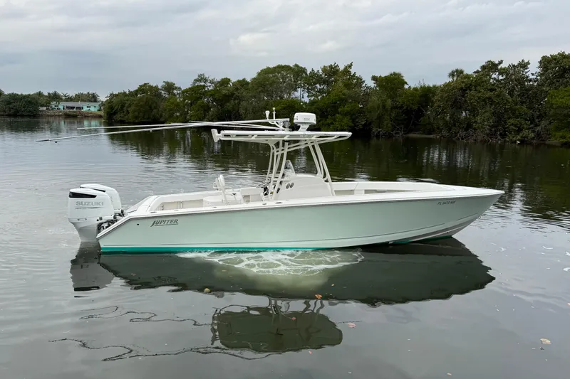 Slide: The Image of 2009 Jupiter 29 boat with Suzuki engine on calm water, surrounded by trees. - 5