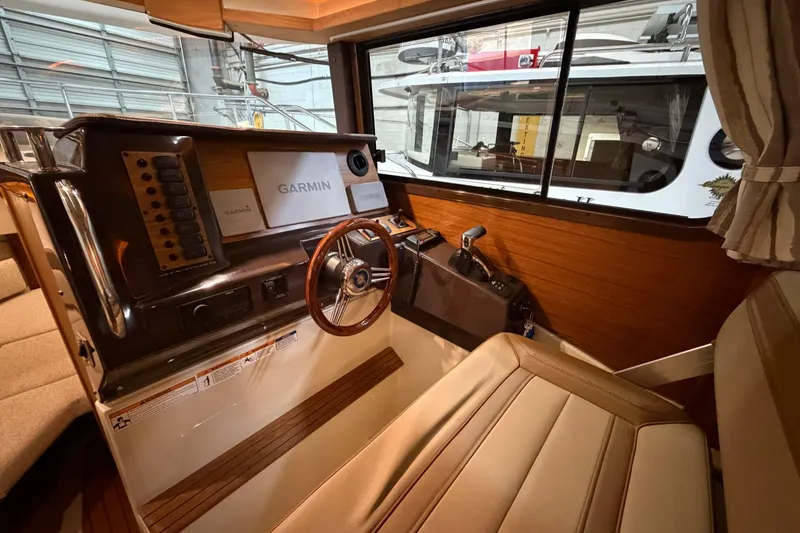 Slide: The Image of 2023 Ranger Tugs R-27 helm with Garmin navigation, wood accents, and comfortable seating. - 15
