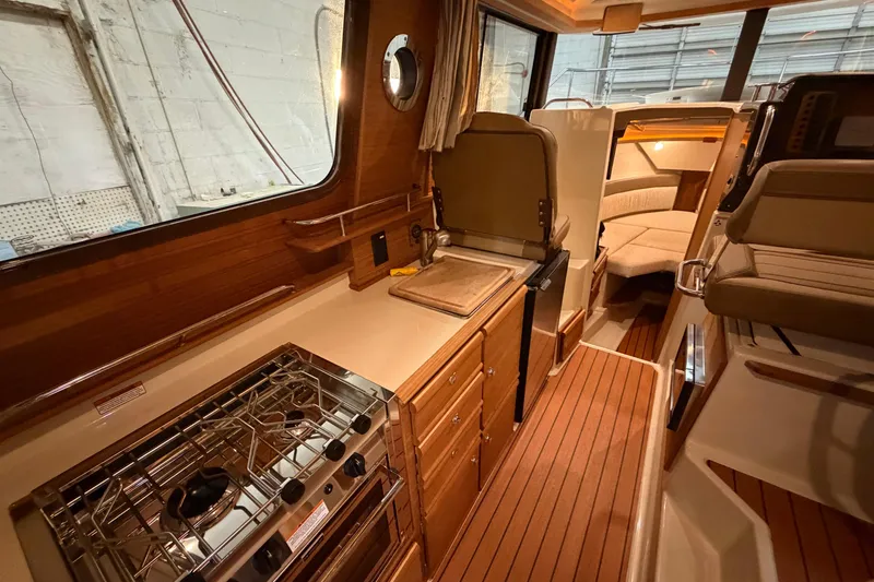 Slide: The Image of 2023 Ranger Tugs R-27 interior with kitchen, seating, and cozy cabin space. - 17