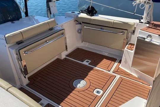 Slide: The Image of 2023 Ranger Tugs R-27 boat interior with teak flooring and cushioned seating. - 5