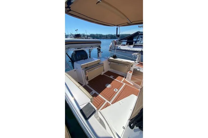 Slide: The Image of 2023 Ranger Tugs R-27 boat interior with teak flooring and seating, docked at marina. - 6