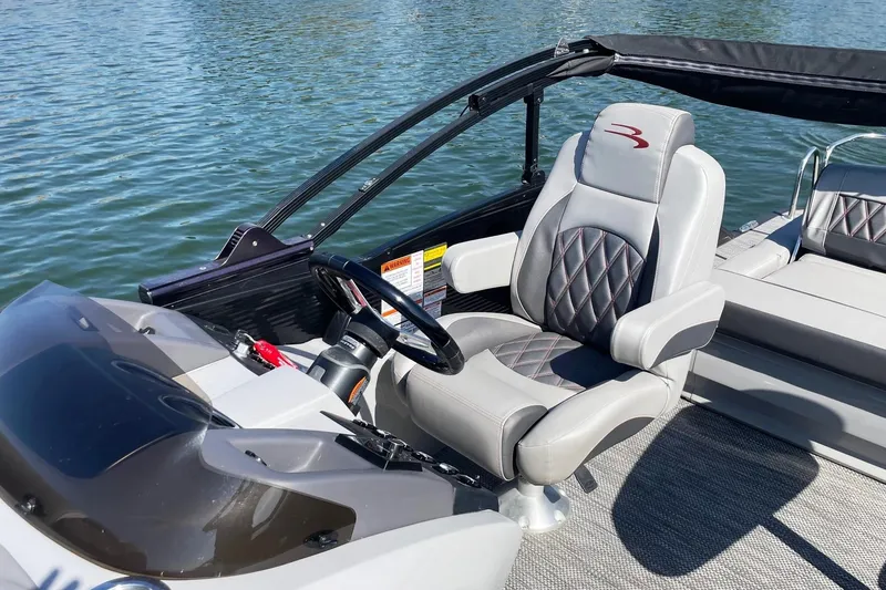 Slide: The Image of 2020 Bennington 22RSB boat interior with captain's chair and steering wheel on water. - 6