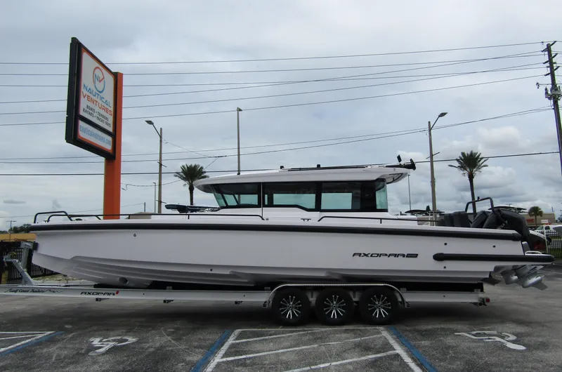 The Image of 2024 Axopar 37XC CROSS CABIN boat on trailer in parking lot. - 0