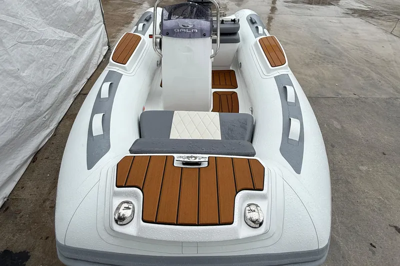 Slide: The Image of 2026 Gala A300L inflatable boat with wood accents on a wet surface. - 2