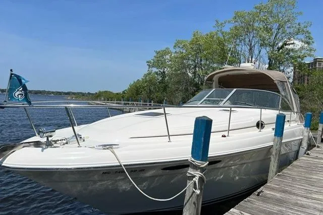 Slide: The Image of 2001 Sea Ray 340 Sundancer docked by a serene lake under a clear blue sky. - 1
