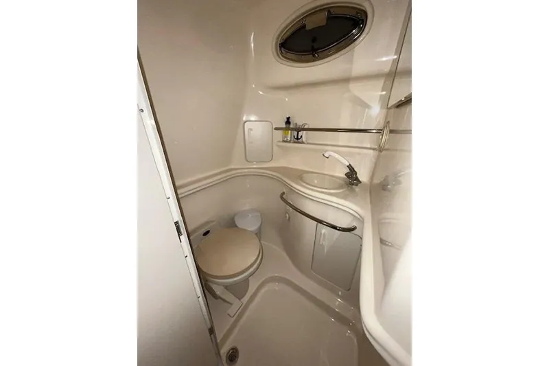 Slide: The Image of Compact bathroom in 2001 Sea Ray 340 Sundancer yacht, featuring toilet, sink, and porthole. - 14