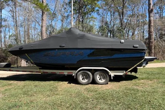 Slide: The Image of 2024 Supra SE 550 boat covered on trailer, parked outdoors. - 2