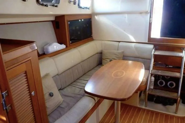 Slide: The Image of Interior of 2002 Island Packet Craft Express 360, featuring cozy seating and wooden table. - 21