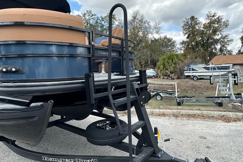Slide: The Image of 2026 Ranger Reata 223FC boat on trailer, parked outdoors with trees in background. - 45