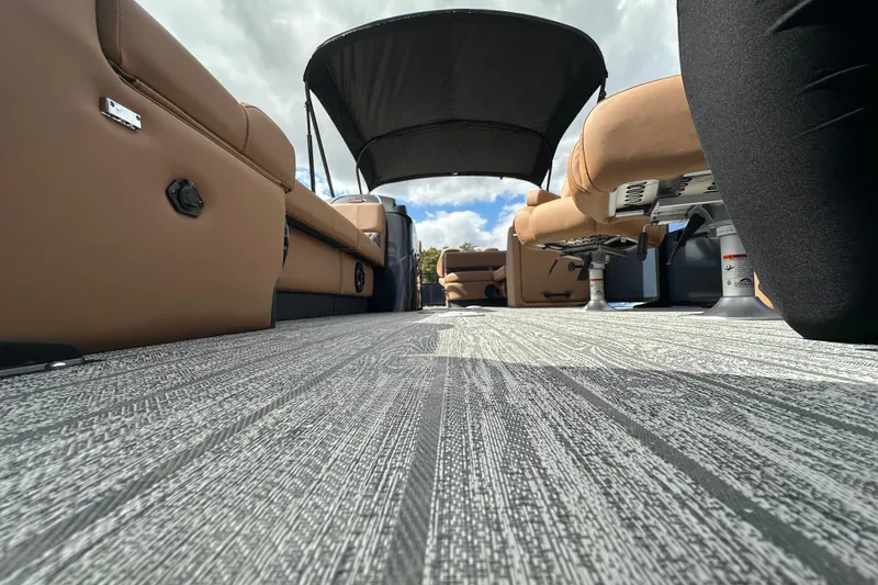 Slide: The Image of 2026 Ranger Reata 223FC boat interior with tan seating and canopy under a cloudy sky. - 7