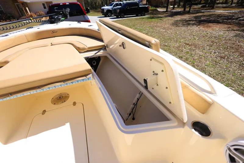 Slide: The Image of 2019 Scout 251 XSS boat interior with tan seating, parked in a residential area. - 17