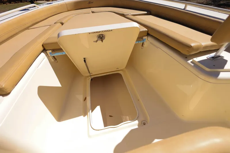 Slide: The Image of 2019 Scout 251 XSS boat interior with open storage compartment and beige seating. - 19