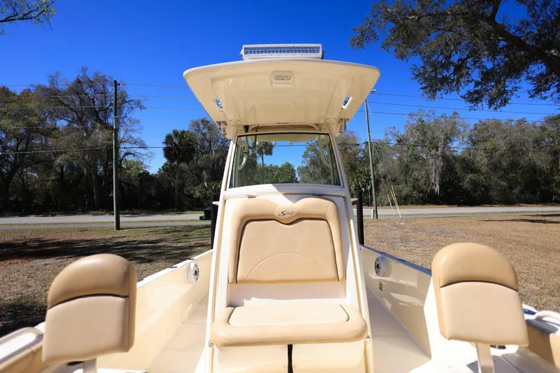 Slide: The Image of 2019 Scout 251 XSS boat with trolling motor on deck, parked on a driveway. - 21