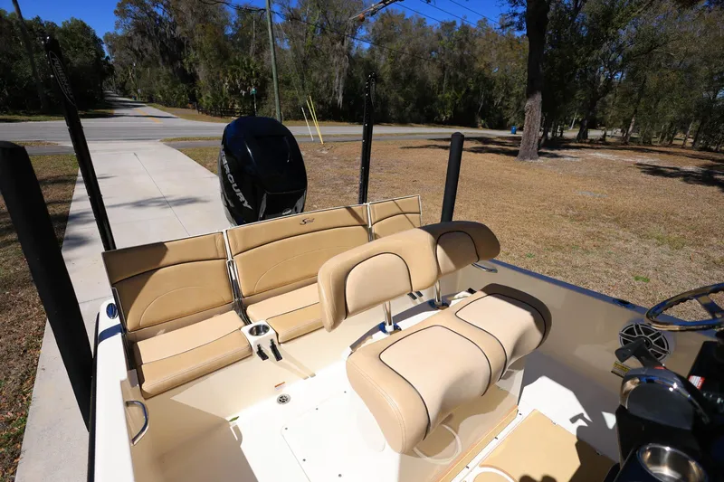 Slide: The Image of 2019 Scout 251 XSS boat interior with seating and console, parked on a sunny day. - 24