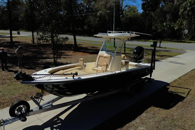 Slide: The Image of 2019 Scout 251 XSS boat on trailer in a driveway, surrounded by trees. - 29