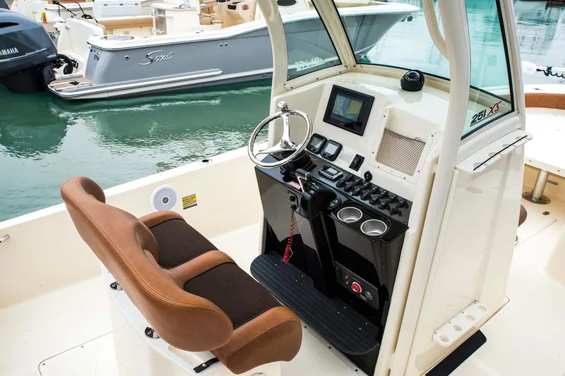 Slide: The Image of 2019 Scout 251 XSS boat with 350 engine, parked on driveway, surrounded by trees. - 6