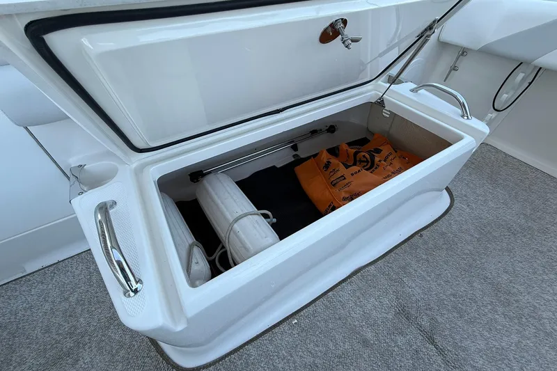 Slide: The Image of Open storage compartment on 2011 Edgewater 205CX Crossover boat, containing safety equipment. - 13