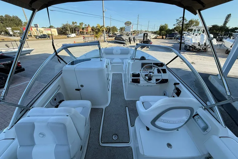Slide: The Image of 2011 Edgewater 205CX Crossover boat interior with steering wheel and seating, parked outdoors. - 19