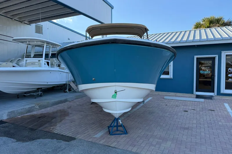 Slide: The Image of 2011 Edgewater 205CX Crossover boat displayed outdoors, blue hull, parked on brick pavement. - 5