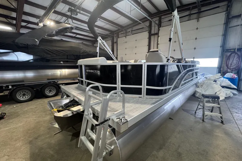 Slide: The Image of 2026 Bennington 20 S-One L-Bench pontoon boat in a garage setting. - 13
