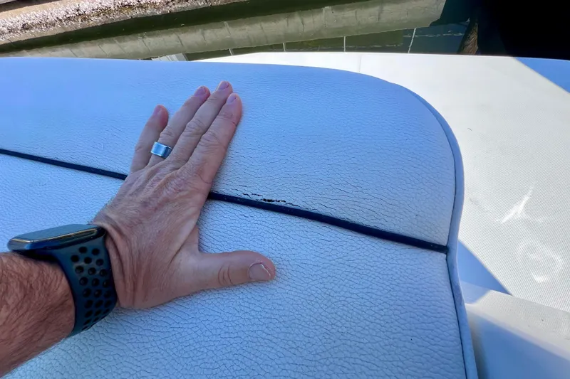 Slide: The Image of Hand inspecting cracked upholstery on 2018 Cruisers Yachts 41 Cantius boat seat. - 95