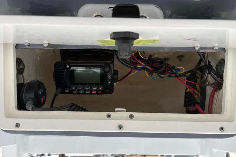 Slide: The Image of 2019 Tidewater 232 CC Adventure boat electronics compartment with wiring and radio equipment. - 16