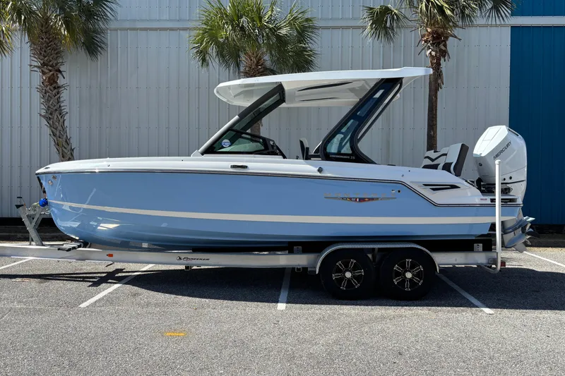 Slide: The Image of 2026 Monterey Elite 25 OB boat on trailer, parked near palm trees. - 1