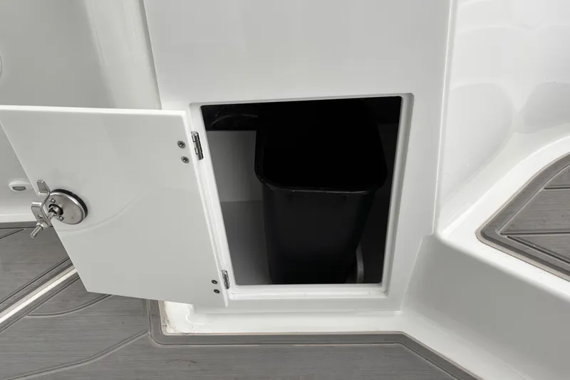 Slide: The Image of Storage compartment on 2026 Monterey Elite 25 OB boat with open door and black bin. - 12