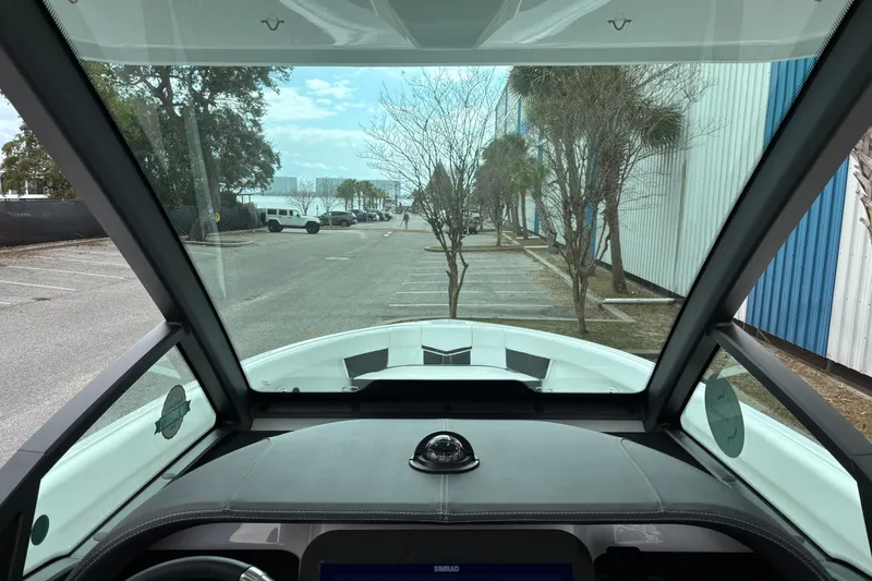Slide: The Image of View from the cockpit of a 2026 Monterey Elite 25 OB boat, parked near trees. - 26