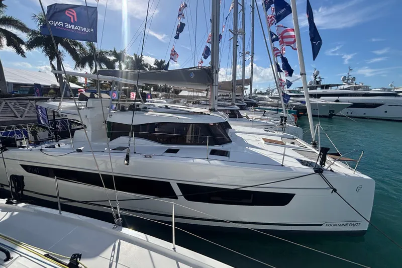 Slide: The Image of 2025 Fountaine Pajot 41 catamaran docked at marina, surrounded by yachts and palm trees. - 51