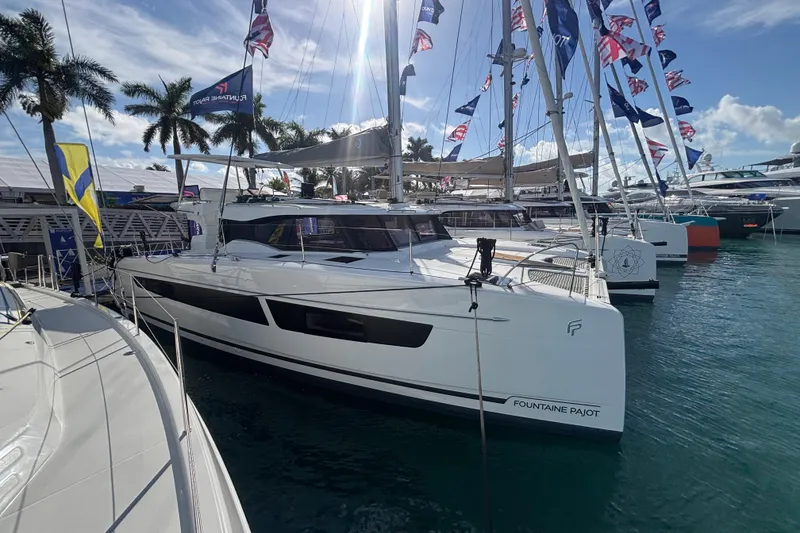 Slide: The Image of 2025 Fountaine Pajot 41 catamaran docked at marina, surrounded by flags and palm trees. - 9