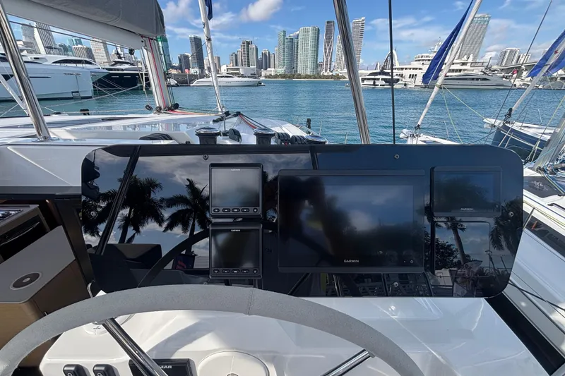 Slide: The Image of 2025 Fountaine Pajot 41 catamaran docked at marina with flags and palm trees. - 2