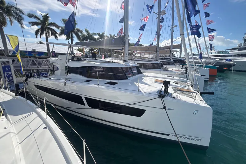 Slide: The Image of 2025 Fountaine Pajot 41 catamaran docked at a marina with flags and palm trees. - 52