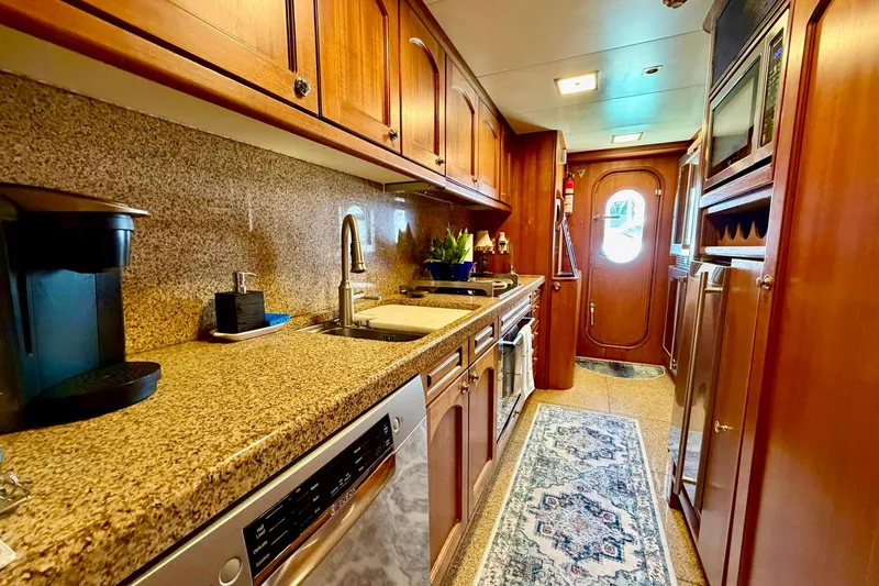 Slide: The Image of Luxurious galley kitchen in 1989 Moonen 85 Long Range Cruiser yacht, featuring wood cabinetry and granite countertops. - 24