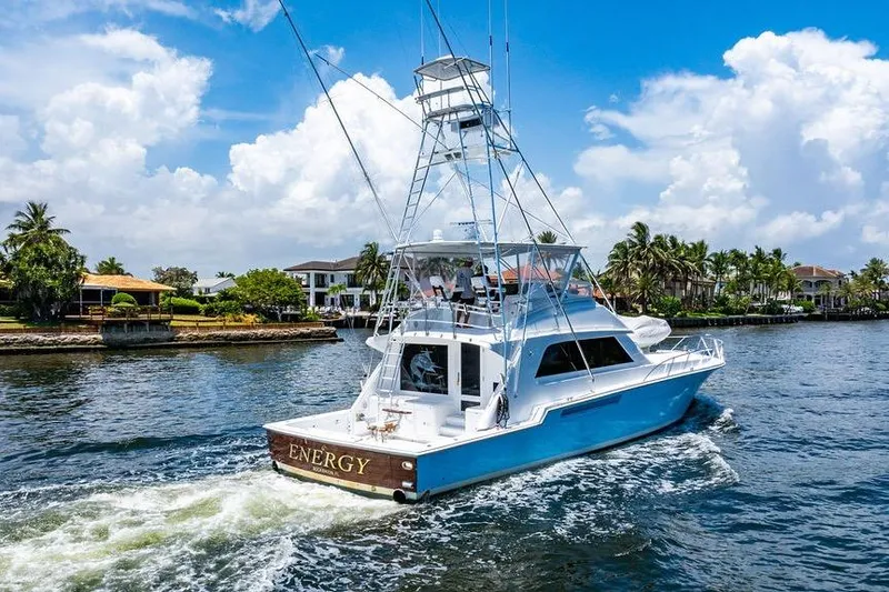 Slide: The Image of 1998 Bertram 60 Convertible yacht cruising on a sunny day near waterfront homes. - 10