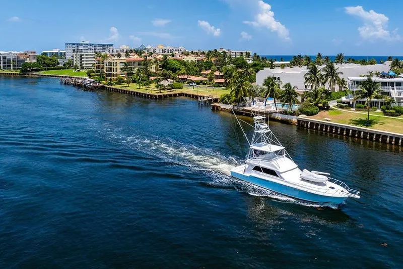 Slide: The Image of 1998 Bertram 60 Convertible yacht cruising near coastal luxury homes and palm trees. - 3