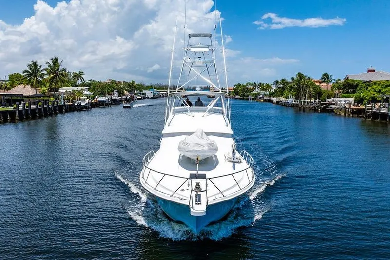 Slide: The Image of 1998 Bertram 60 Convertible yacht cruising on a scenic waterway under a clear blue sky. - 4
